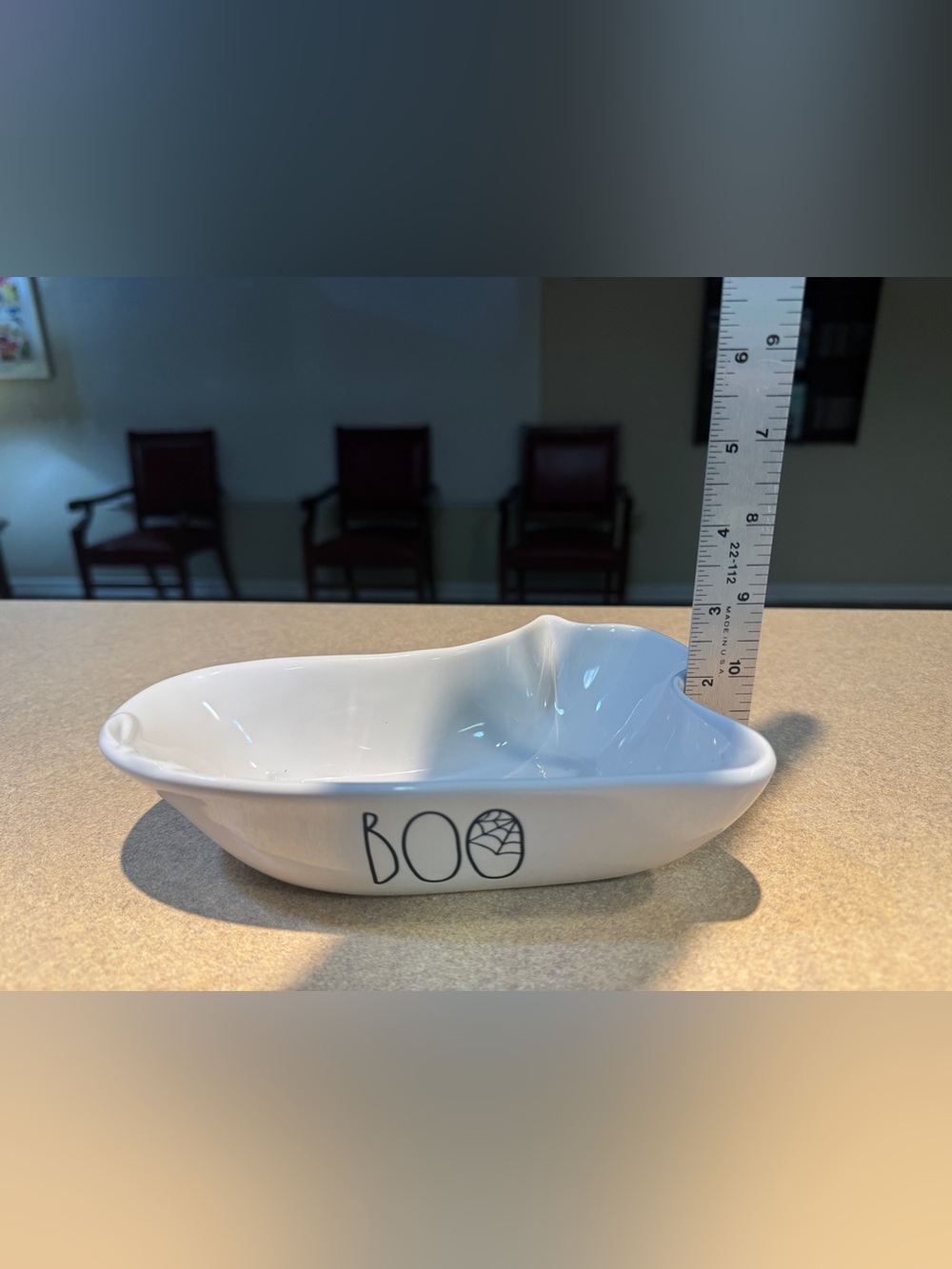 White ceramic ghost-shaped dish with 'BOO' text by Rae Dunn